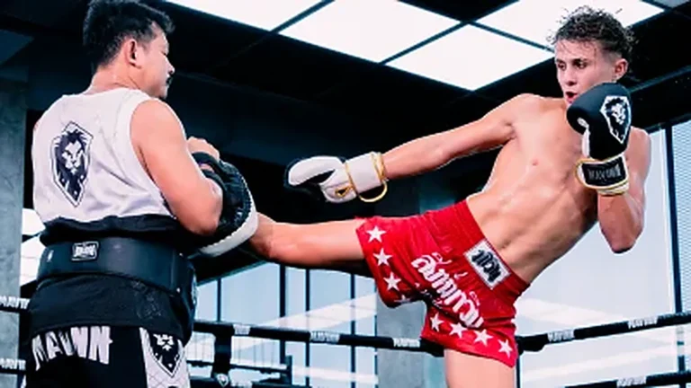 Home Fighter landing a body kick on the trainer pads inside the MAVINN ring