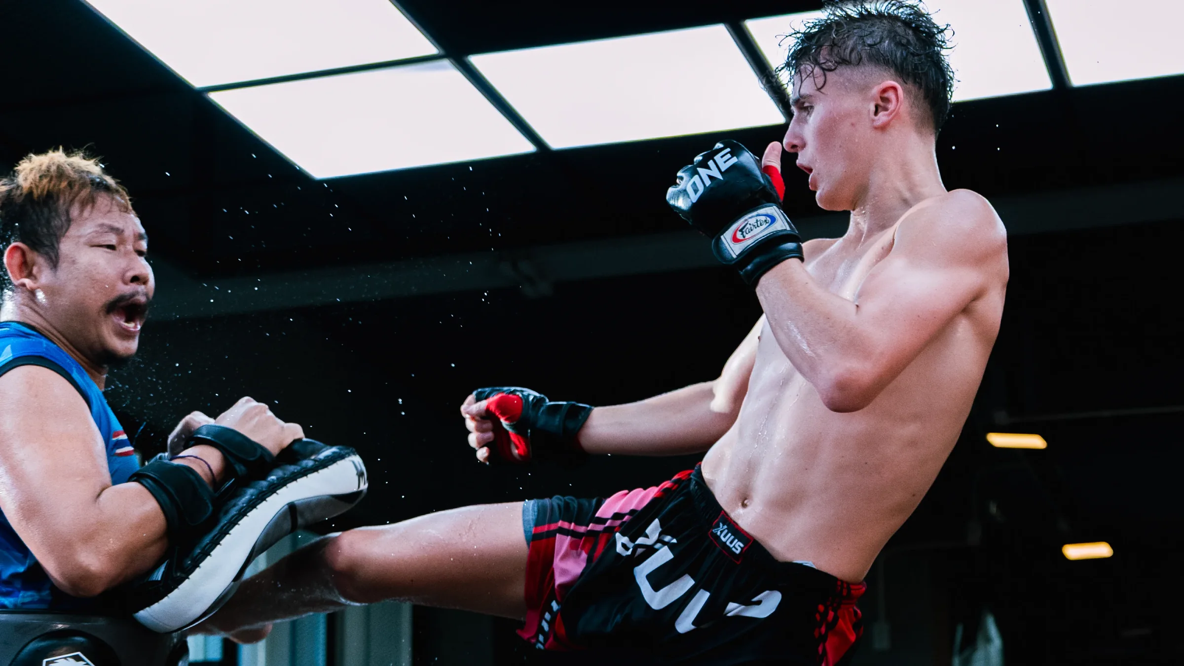 Testimonials Student landing a kick on Thai pads held by a MAVINN trainer