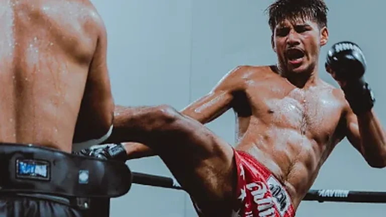 Home Fighter driving a kick through the pads during a hard round at MAVINN
