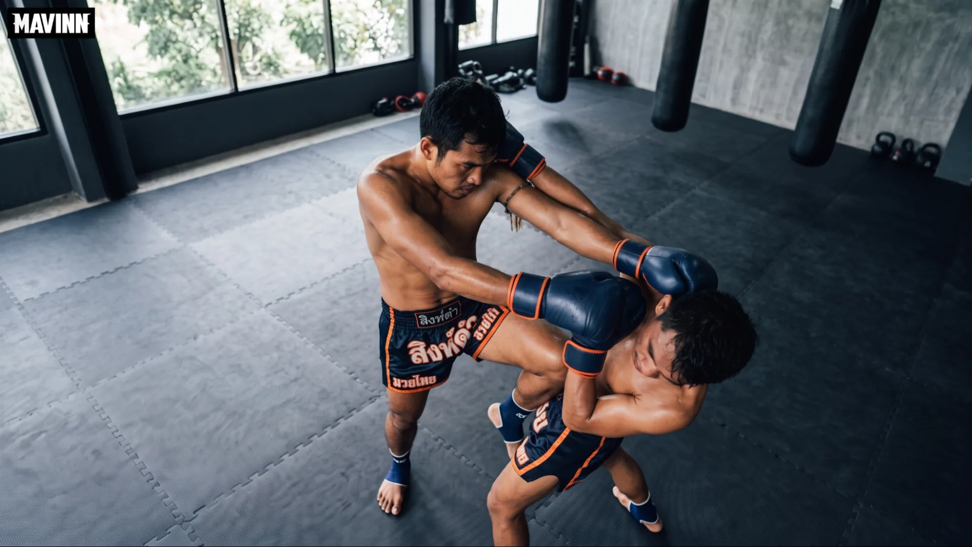 Fighter driving a knee into an opponent who is bent over on the mats